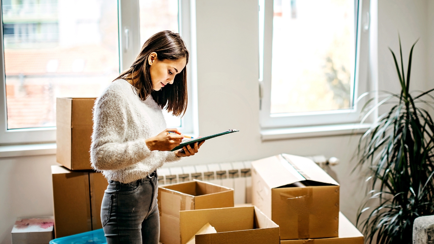 A woman standing in front of boxes looking at a tablet