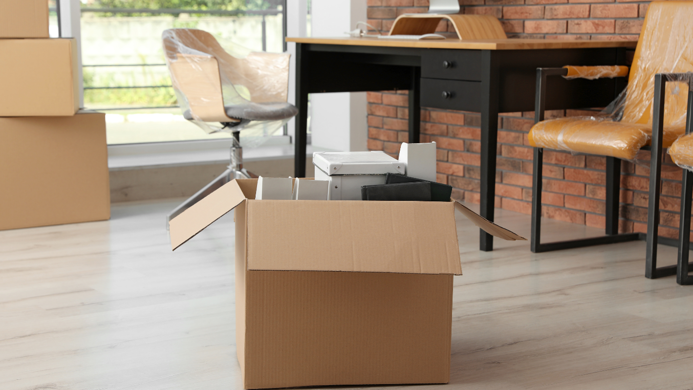 A cardboard box sitting on the floor in front of a brick wall