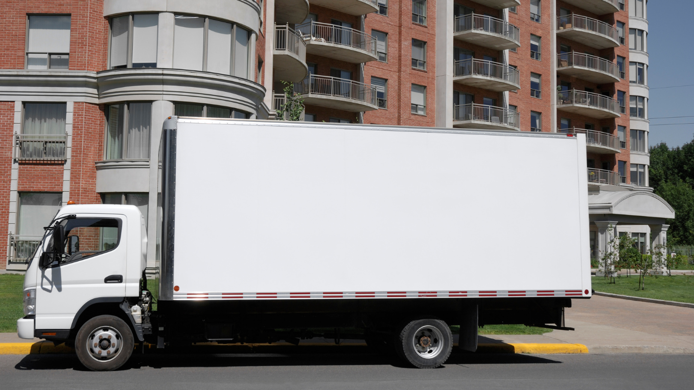 A large white box truck parked in front of a building