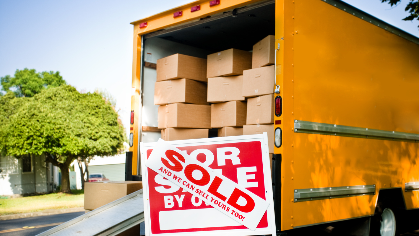 A yellow moving truck with a for sale sign in the back