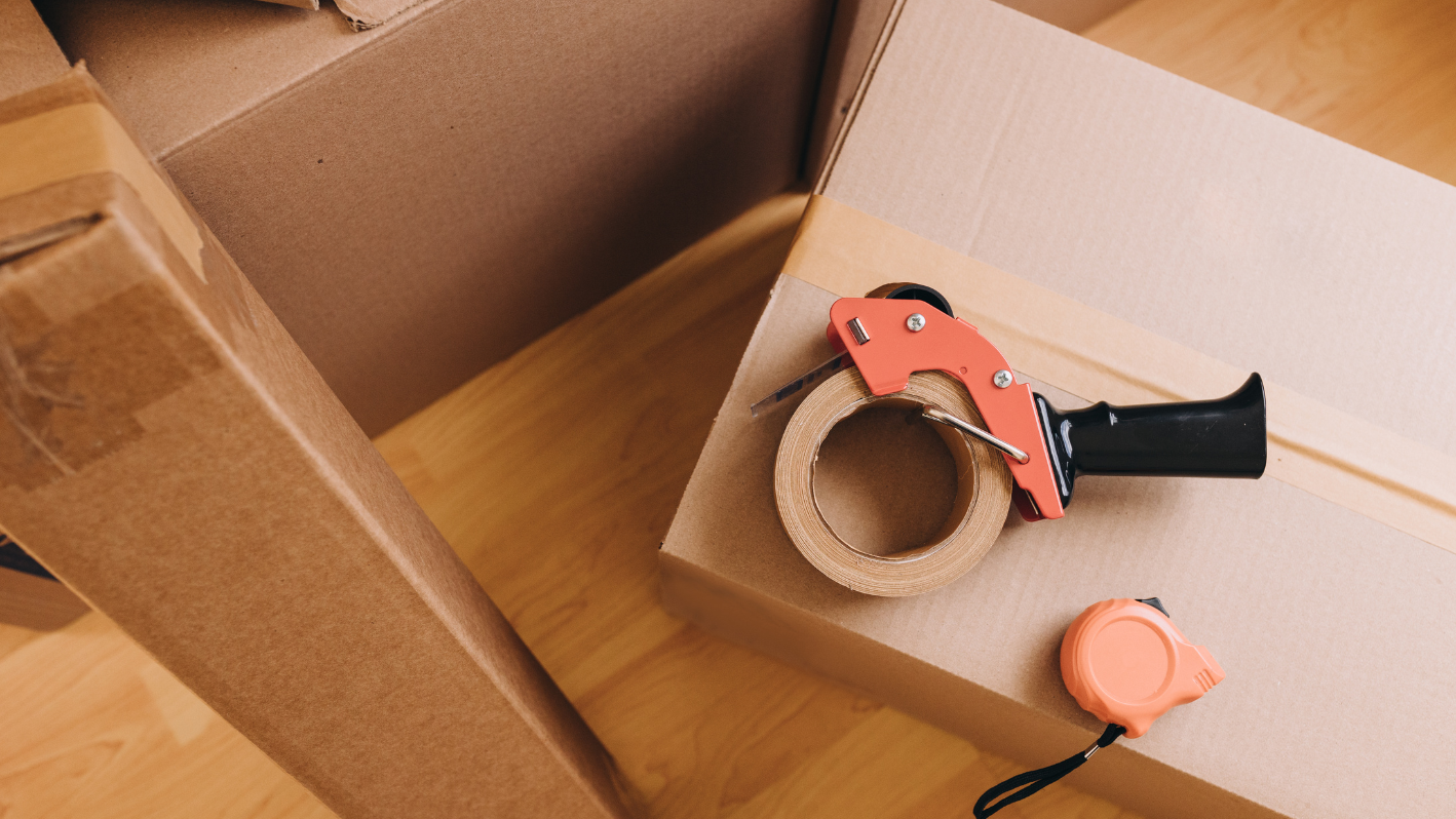 A box with a pair of scissors and a tape dispenser