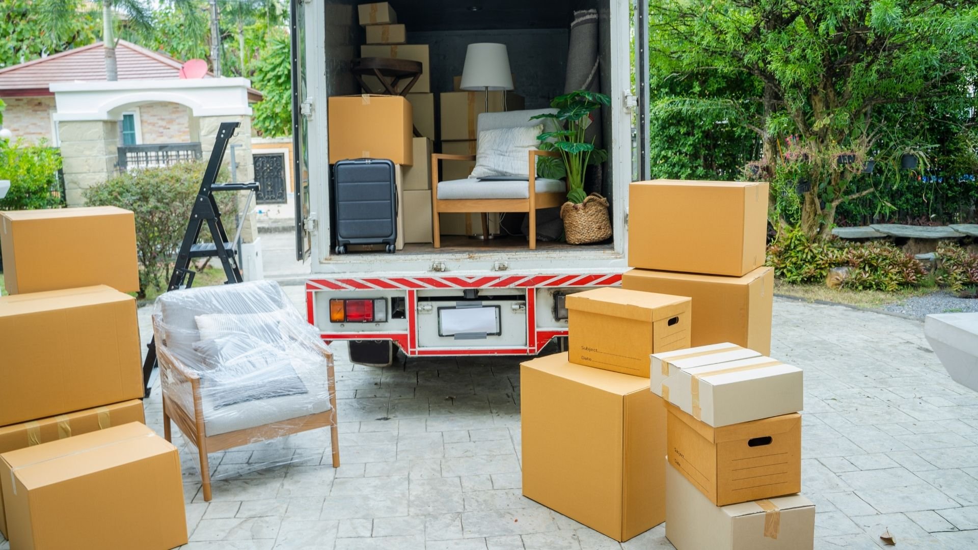 Moving day scene with boxes, furniture, and trailer in an Orange County driveway