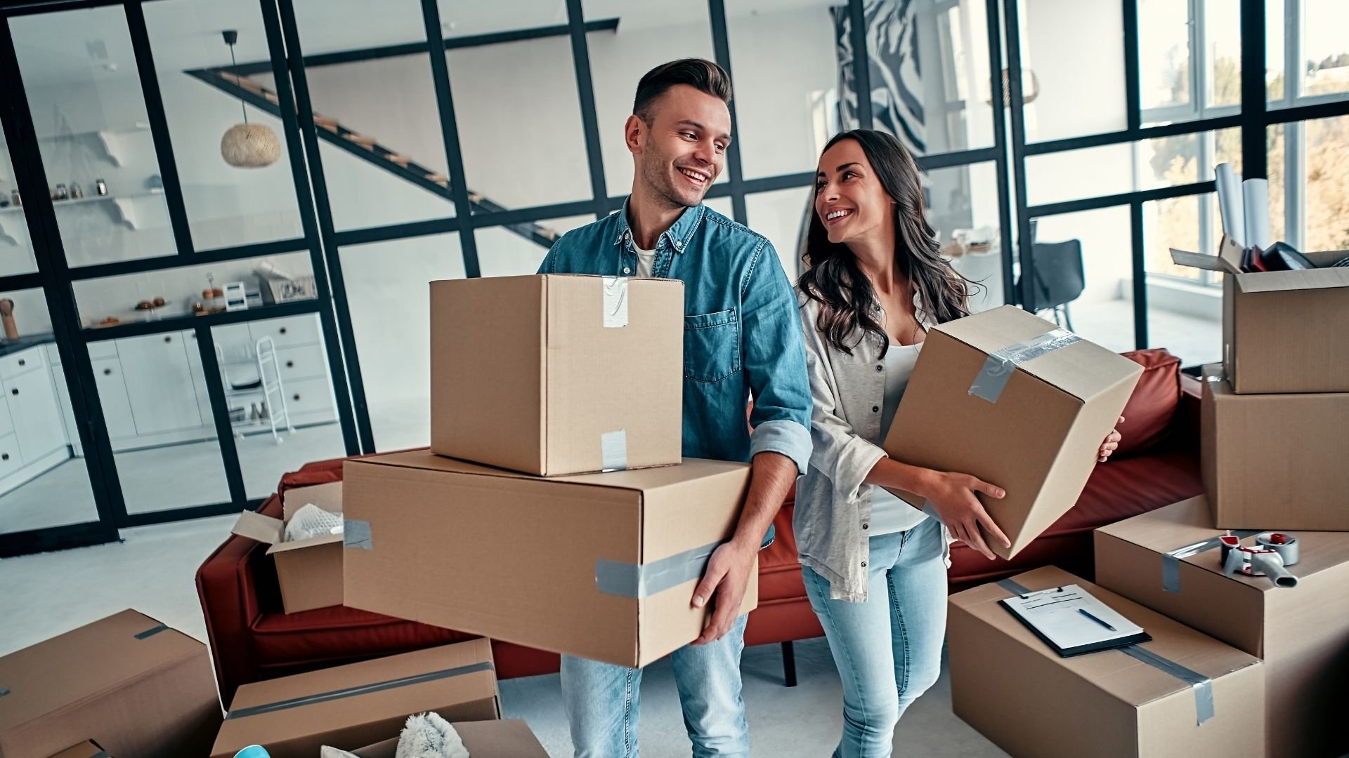 Happy couple moving into a bright modern apartment with boxes